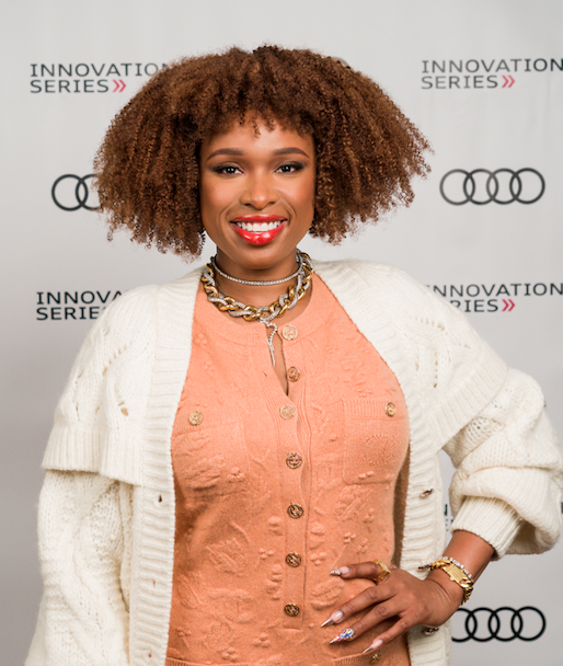 Jennifer Hudson in white cardigan and peach blouse against Audi backdrop
