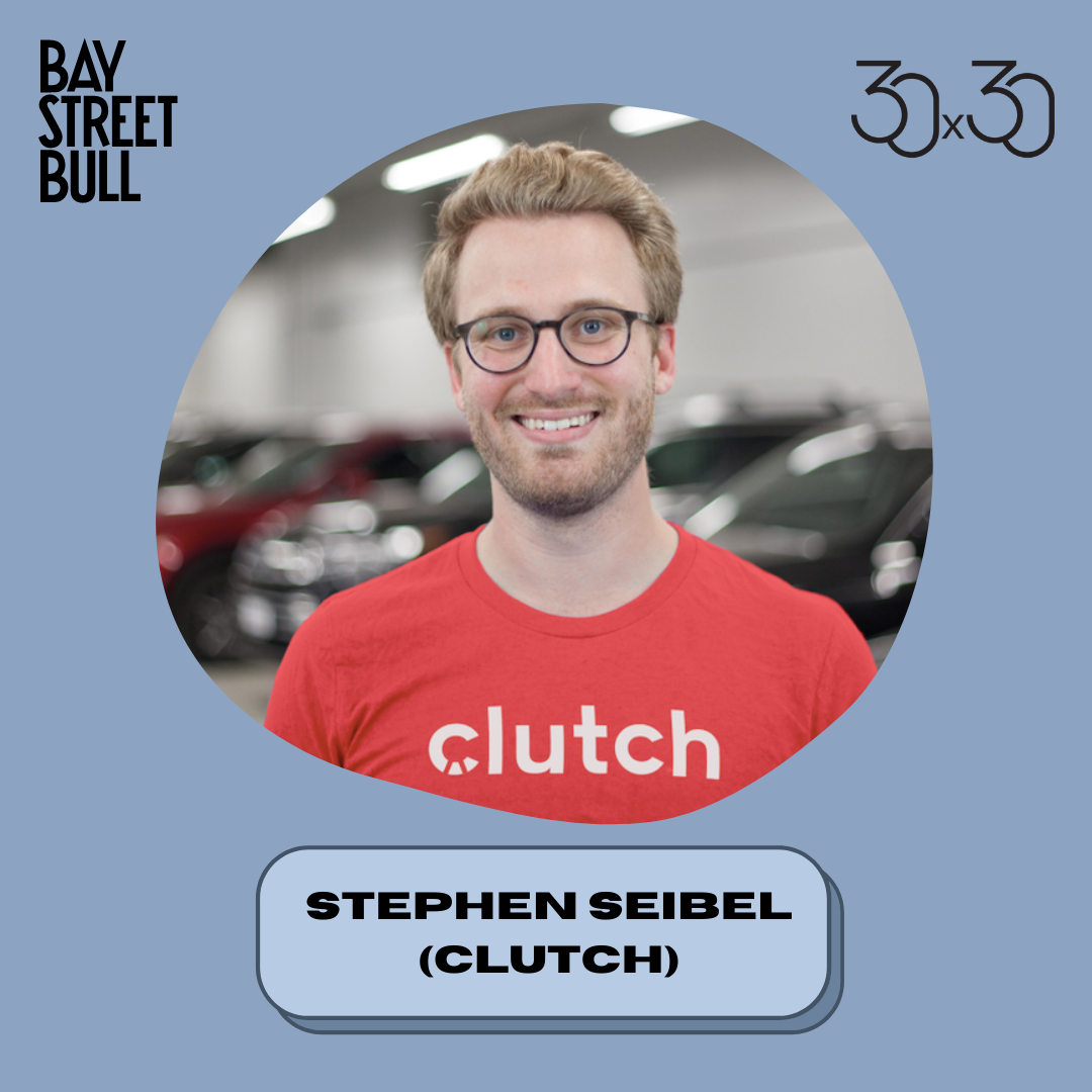 Man wearing red shirt that says "clutch" smiling and wearing glasses against parked cars