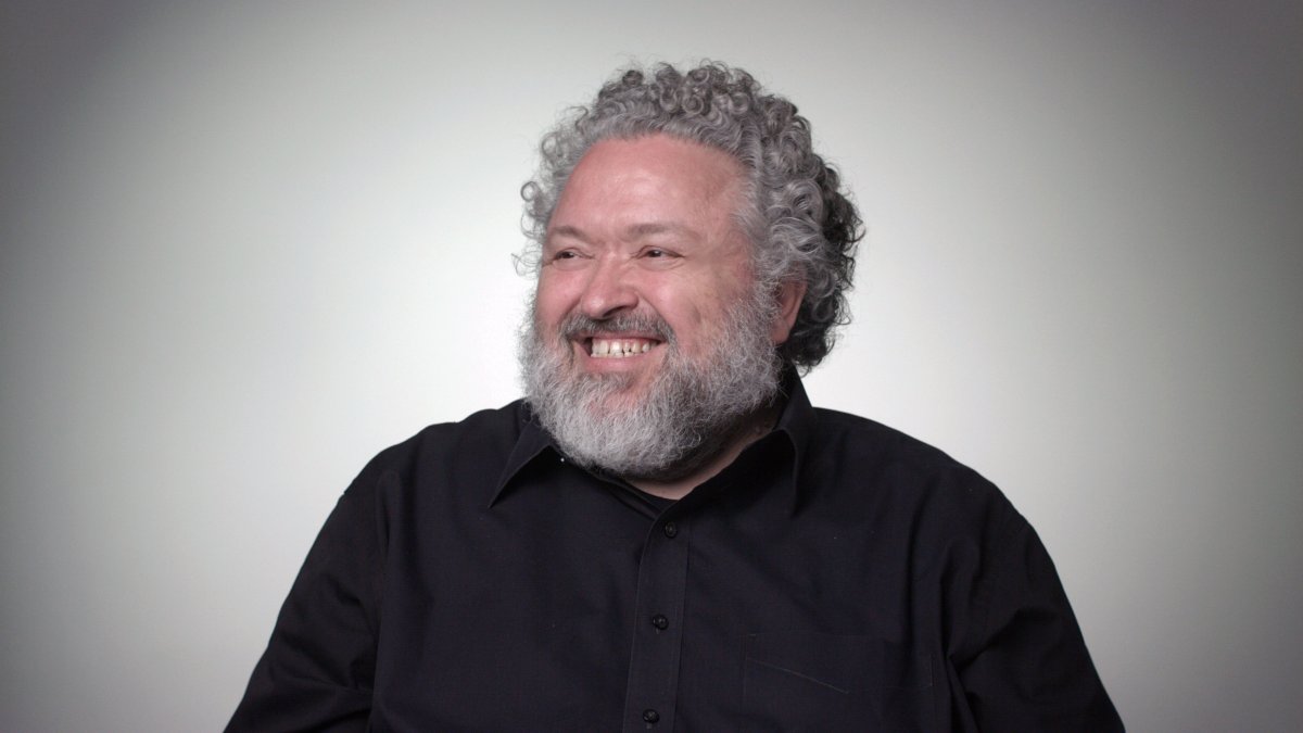 Portrait of designer Bruce Mau smiling and wearing a black shirt.