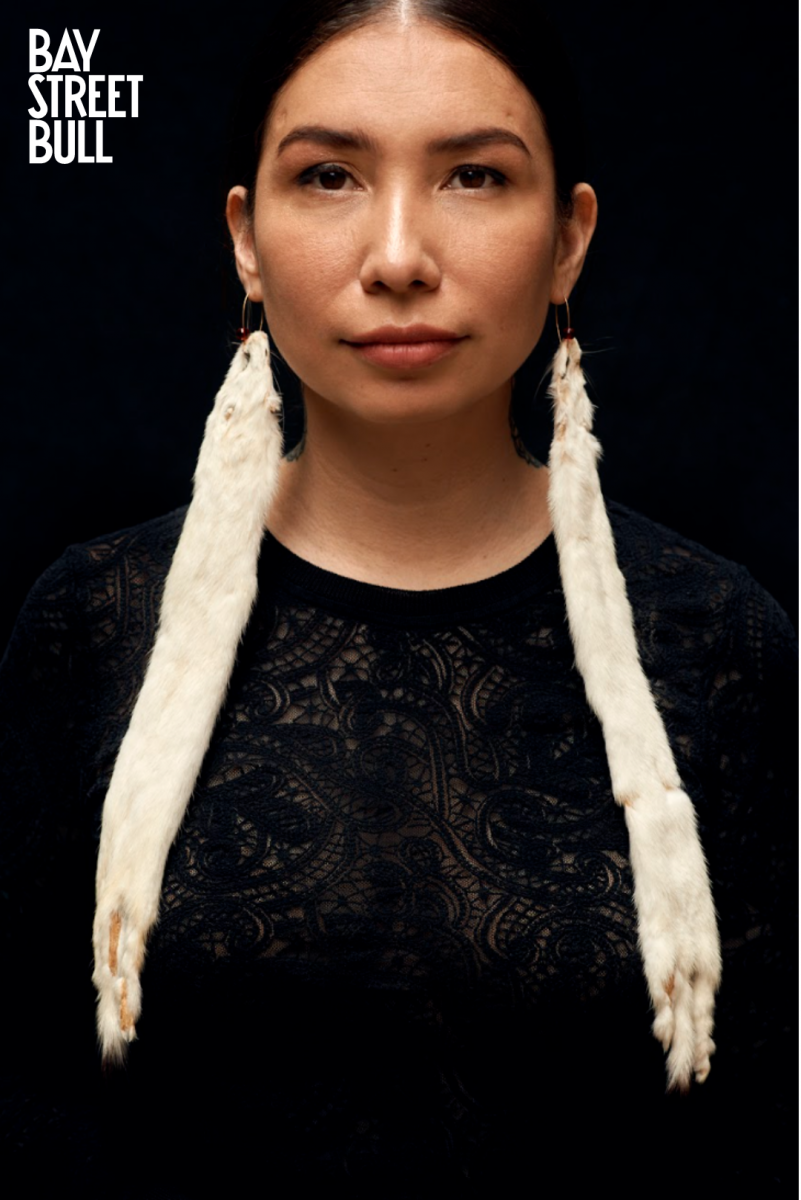 Sage Paul wearing black dress and earrings made of white mink-like animal
